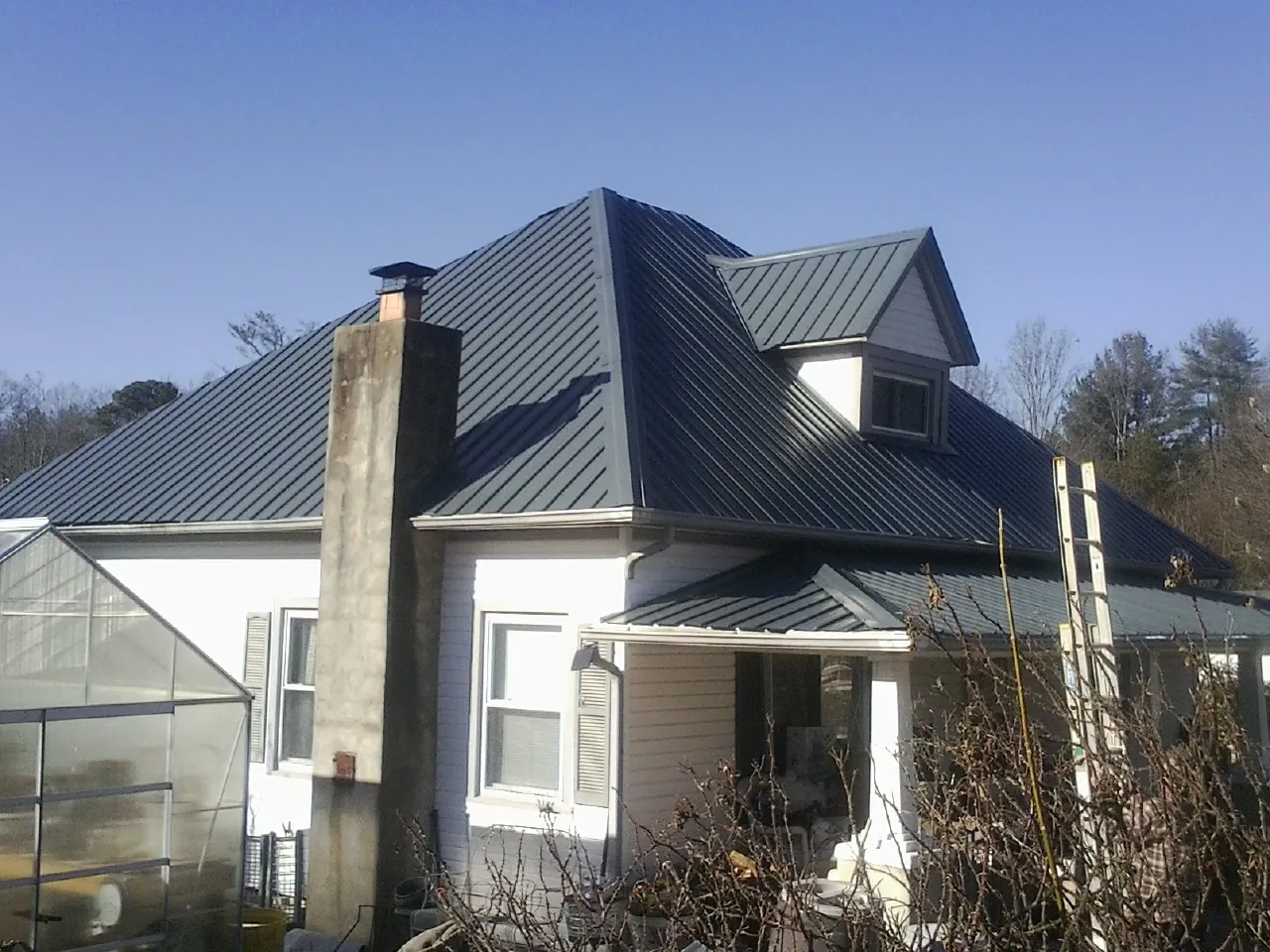 Dark blue standing seam metal roof on a white farmhouse with dormer — Slate & Tile Roof Repair by Roofing Brothers in Shelocta