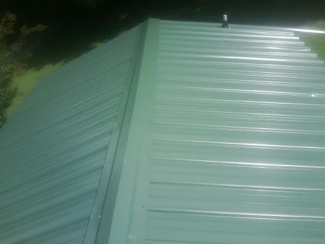 New green metal panels meeting at the ridge of a roof — Flat Roof Repair work by our crew in Shelocta