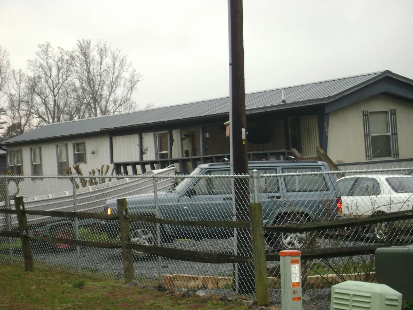 Dark metal roof on a long single story building behind a chain link fence in Shelocta