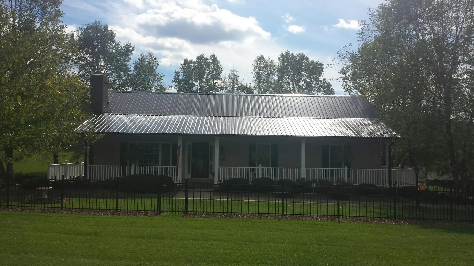 Gray metal roof on a brick ranch with a full width front porch — Gutter Guard Installation work by our crew in Shelocta