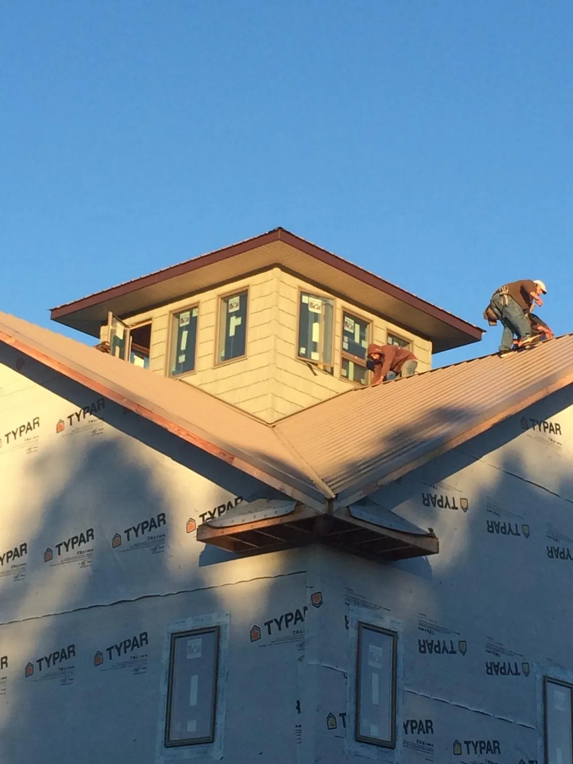 Roofers working around a rooftop cupola on a new metal roof at sunset — Roof Waterproofing in Shelocta by Roofing Brothers